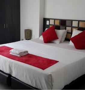 un letto con cuscini rossi e bianchi di AW Hotel Ariston a Bogotá