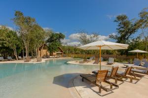a swimming pool with chairs and an umbrella at Lumina at The Village Luxury Residences in Corasol in Playa del Carmen