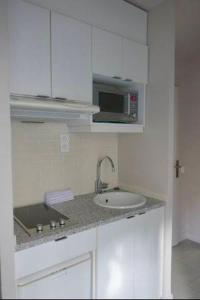 a white kitchen with a sink and a microwave at Pousada Village Paraty Centro in Paraty