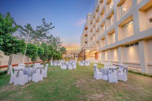 een groep witte tafels en stoelen voor een gebouw bij Regenta Dehradun by Royal Orchid Hotels Limited in Dehradun