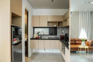 a kitchen with brown cabinets and a couch in a room at M Village Nguyễn Văn Thủ in Ho Chi Minh City