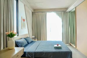 a bedroom with a blue bed and a large window at M Village Nguyễn Văn Thủ in Ho Chi Minh City