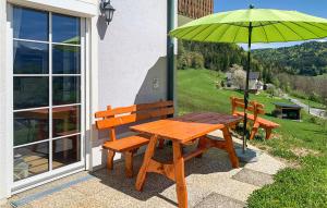 una mesa de madera y un banco con una sombrilla verde en Gorgeous Apartment In Schiefling Am Wrthers, With Kitchen, en Sankt Egyden