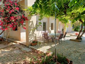un patio con mesa, sillas y flores en The Grapevine Guest House, en Pafos