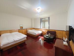 Habitación con 2 camas, mesa y TV. en Chia Yuen Homestay, en Fenchihu