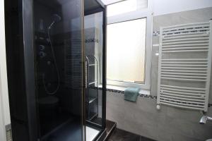 uma casa de banho com uma cabina de duche em vidro e uma janela. em Chic Apartment with Balcony em Wuppertal