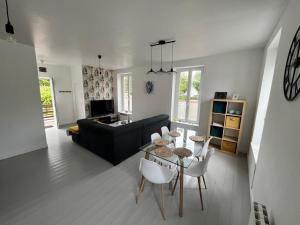 a living room with a black couch and a table and chairs at Gîte de la gare - avec parking in Hesdigneul-lès-Boulogne