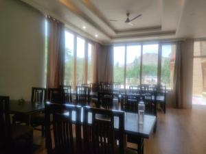 a dining room with tables and chairs and windows at Hotel Alpine Ladakh in Leh