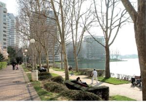 people sitting on benches in a park near the water at Central Hotel in Créteil