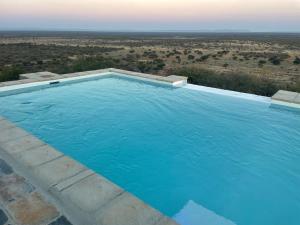 a swimming pool with a view of the desert at Aloegrove Safari Lodge in Otjiwarongo