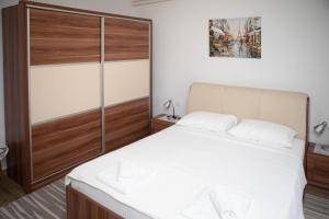 - une chambre avec un lit blanc et un placard en bois dans l'établissement Apartmani Budimčić, à Trebinje