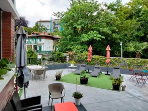 un patio con sillas, mesas y sombrillas en Doma Etxea Donostia-San Sebastian, en San Sebastián