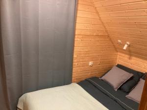 a small bed in a room with a wooden wall at Domek nad rzeką in Wierzchlas +55 photos