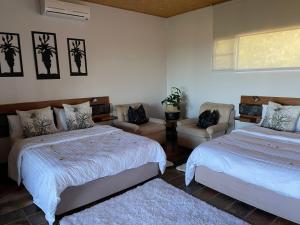 a bedroom with two beds and a chair and a window at Aloegrove Safari Lodge in Otjiwarongo