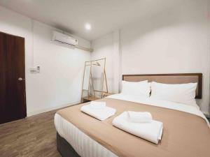 ein Schlafzimmer mit einem großen Bett mit zwei weißen Handtüchern darauf in der Unterkunft Ray's Home,3BR with front yard,walkable to Nimman in Chiang Mai