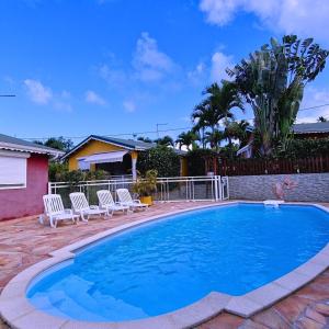 a swimming pool in a yard with chairs around it at Atlantic Gites in Capesterre-Belle-Eau