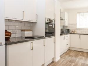 a white kitchen with white cabinets and appliances at The Garden House in Whitstable