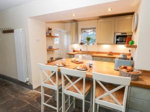 eine Küche mit einem Holztisch und weißen Stühlen in der Unterkunft Hope View House in Castleton