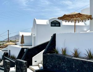 a white building with an umbrella and some plants at Venus Sunrise Suites & Villas in Vourvoúlos