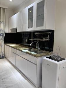 a kitchen with white cabinets and a sink and a refrigerator at Mộc Homestay VIP in Ấp Ðông An (1)