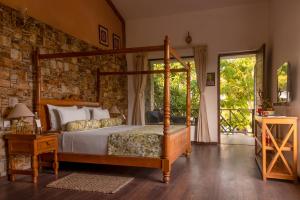 a bedroom with a canopy bed and a stone wall at Tree of Life Vanvilas Riveredge Corbett in Rāmnagar