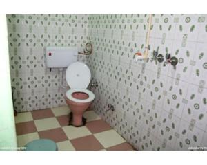 a bathroom with a toilet in a small room at Hotel Jagatguru, Barkot in Barkot