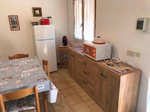 a kitchen with a table and a white refrigerator at Eden Beach, trilocale con giardino a pochi passi dal mare in Sorso