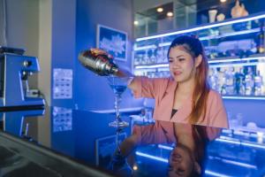 a woman pours a drink into a wine glass at Noble House Patong in Patong Beach
