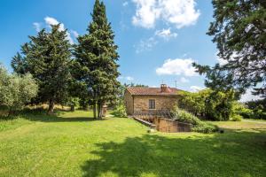 una vieja casa de piedra en un campo con árboles en Villa Agriturismo Il Pratone, en Castiglione dʼOrcia