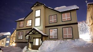 una casa está cubierta de nieve por la noche en Niseko Alpine Apartments en Niseko