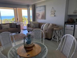 sala de estar con sofá, mesa y sillas en Laguna La Crete 13, en Uvongo Beach