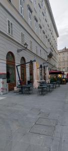 a large building with tables and benches in front of it at Appartamento Tergesteo in Trieste