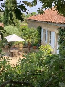 un jardín con una mesa y una sombrilla y una casa en Chambre d'hôtes à Mignaloux-Beauvoir- le Thil en Mignaloux-Beauvoir