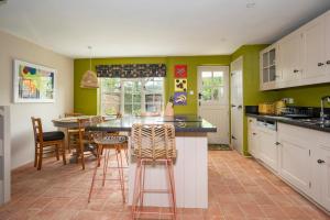 a kitchen with green walls and a counter with stools at Pats' Place Long Melford in Sudbury