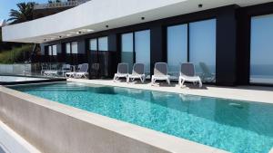 a swimming pool with chairs next to a building at Villa El Buzo in Zahara de los Atunes