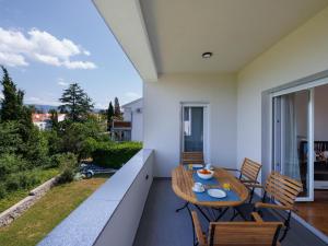 a patio with a wooden table and chairs on a balcony at Apartment in ilo on Krk Island in Šilo