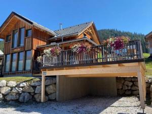 ein Haus mit einer Terrasse mit Blumen darauf in der Unterkunft Chalet in Hohentauern Styria with sauna in Hohentauern