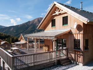 a house with a deck and mountains in the background at Chalet in Hohentauern Styria with sauna in Hohentauern