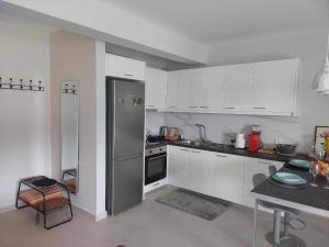 a kitchen with white cabinets and a stainless steel refrigerator at Gesyl Apartment in Tolo
