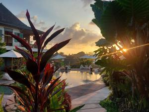 a pool at a resort with a sunset in the background at Spaces Bali Unique Boutique Hotel in Munggu