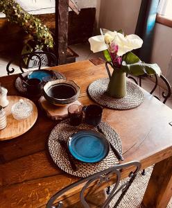 una mesa de madera con platos y un jarrón con flores en Au Bien Hêtre, en Futeau