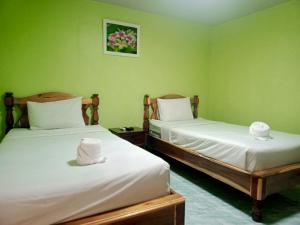two beds in a room with green walls at บ้านนารีสอร์ท in Nakhon Nayok