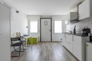 Una cocina con gabinetes blancos y una mesa y sillas. en Station Apartment, en Pisa
