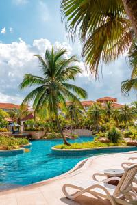 uma piscina no resort com palmeiras e cadeiras em Sheraton Haikou Hotel em Haikou