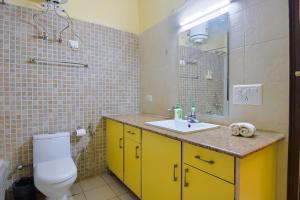 ein Badezimmer mit einem WC, einem Waschbecken und einem Spiegel in der Unterkunft Studio Serviced Apartments near Fortis Hospital in Gurgaon