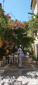 a patio with tables and chairs under a tree with pink flowers at Vice Versa Elegant Studio 1 in Nafplio