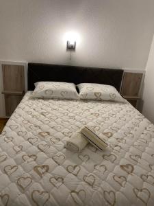 a bed with a white bedspread with hearts on it at Apartmani Vasković in Trebinje