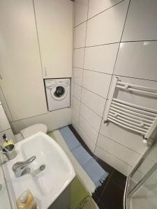 a bathroom with a sink and a washing machine at Your Apart Saska Kępa in Warsaw