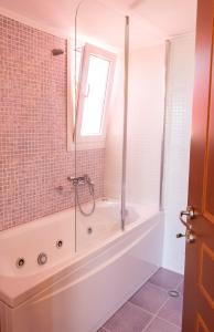 a bathroom with a shower and a tub with a window at Argo Studios in Giosonas