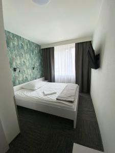 ein kleines Bett in einem Zimmer mit Fenster in der Unterkunft Jantar Resort in Stettin
